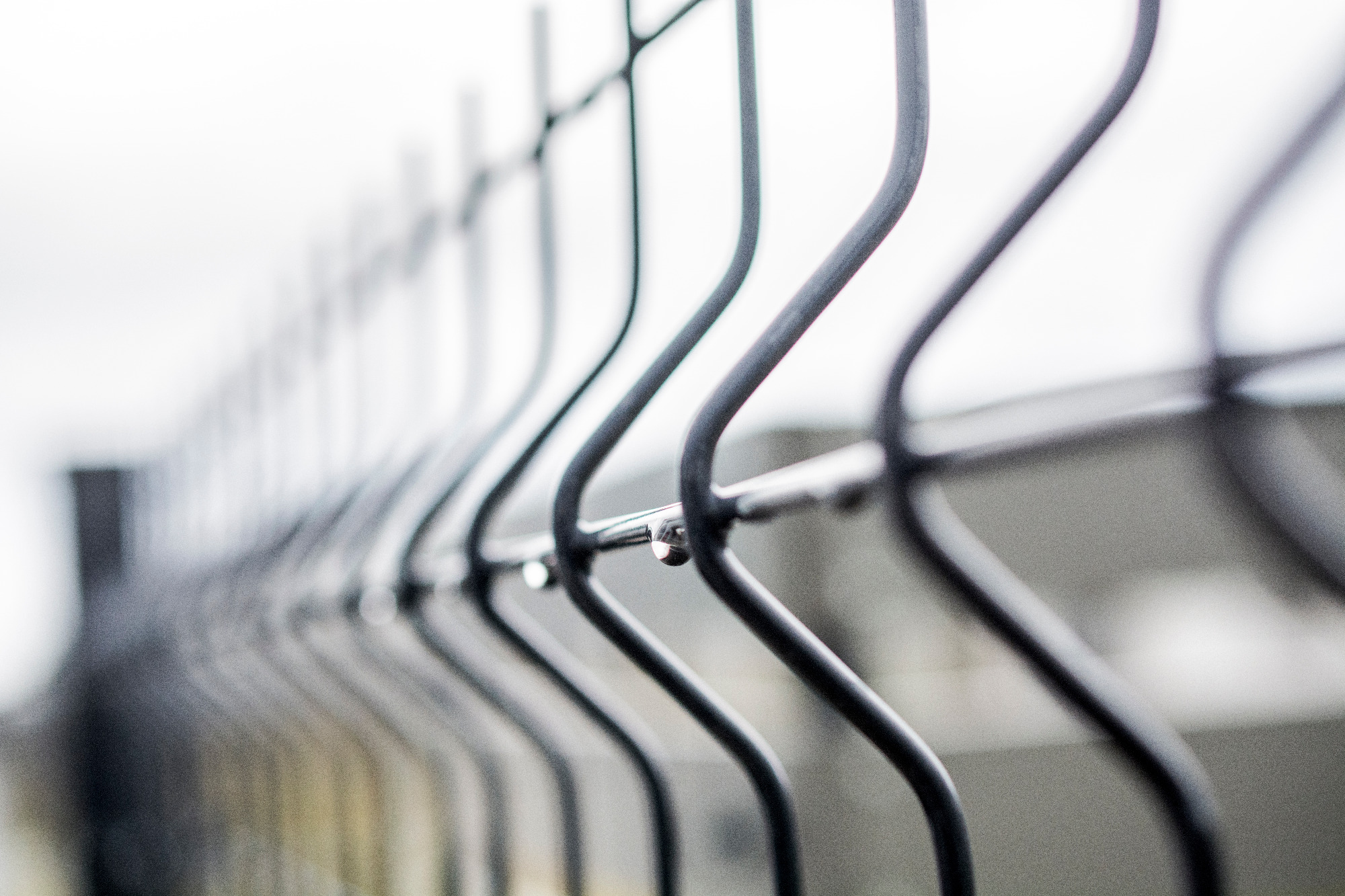 Metalowe ogrodzenie z kroplami deszczu, widok z bliska, pochmurny dzień.