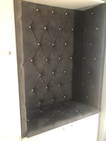 Wnęka z siedziskiem obita ciemnoszarym welurem w romby, zdobiona kryształkami, wbudowana w białą szafę.