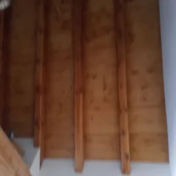 Drewniana konstrukcja poddasza z widocznymi belkami i deskami, świeżo pomalowana na biało dolna część ściany.