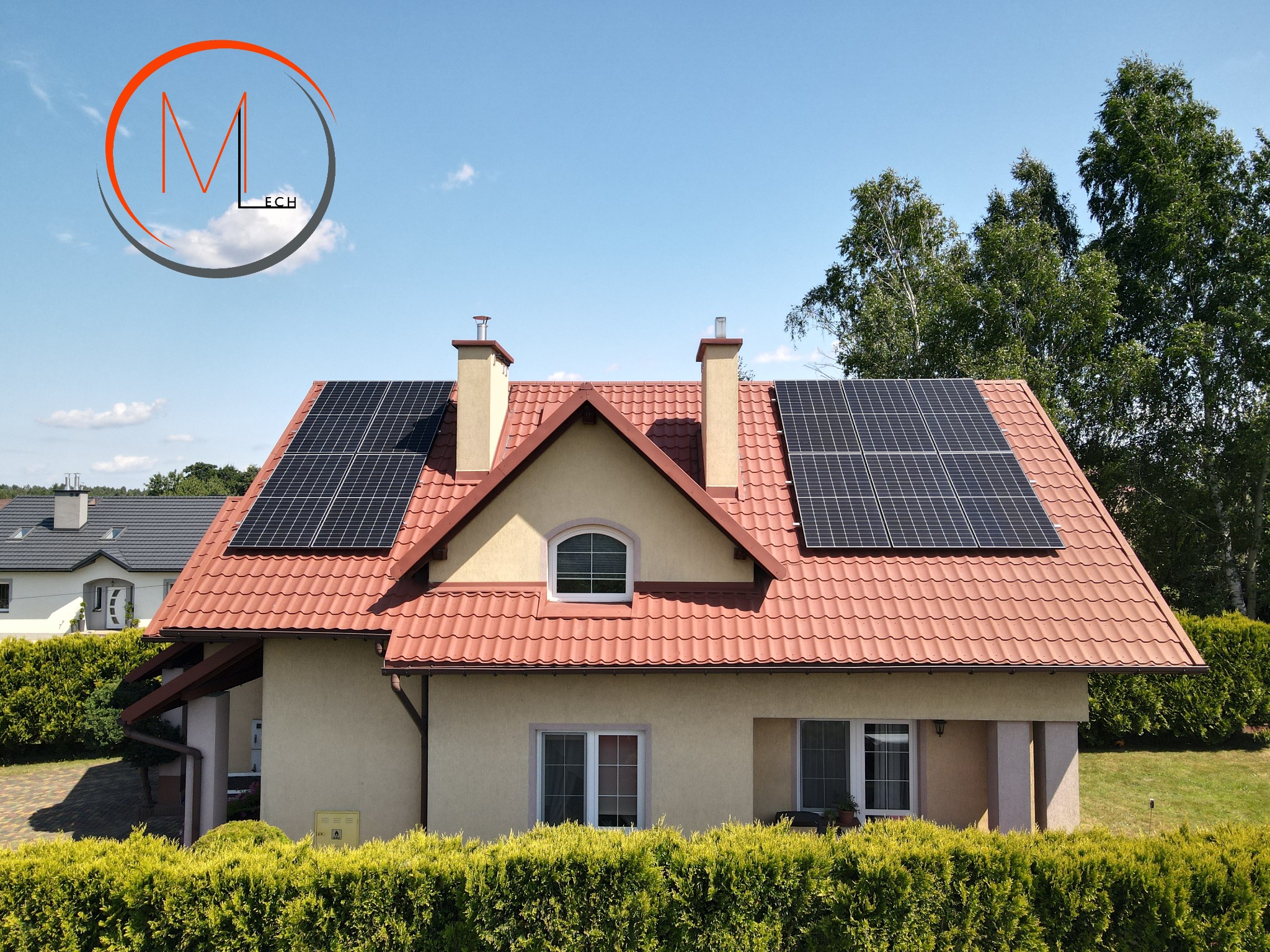 Dom jednorodzinny z czerwoną dachówką i panelami słonecznymi na dachu, widoczne kominy i logo firmy w lewym górnym rogu.
