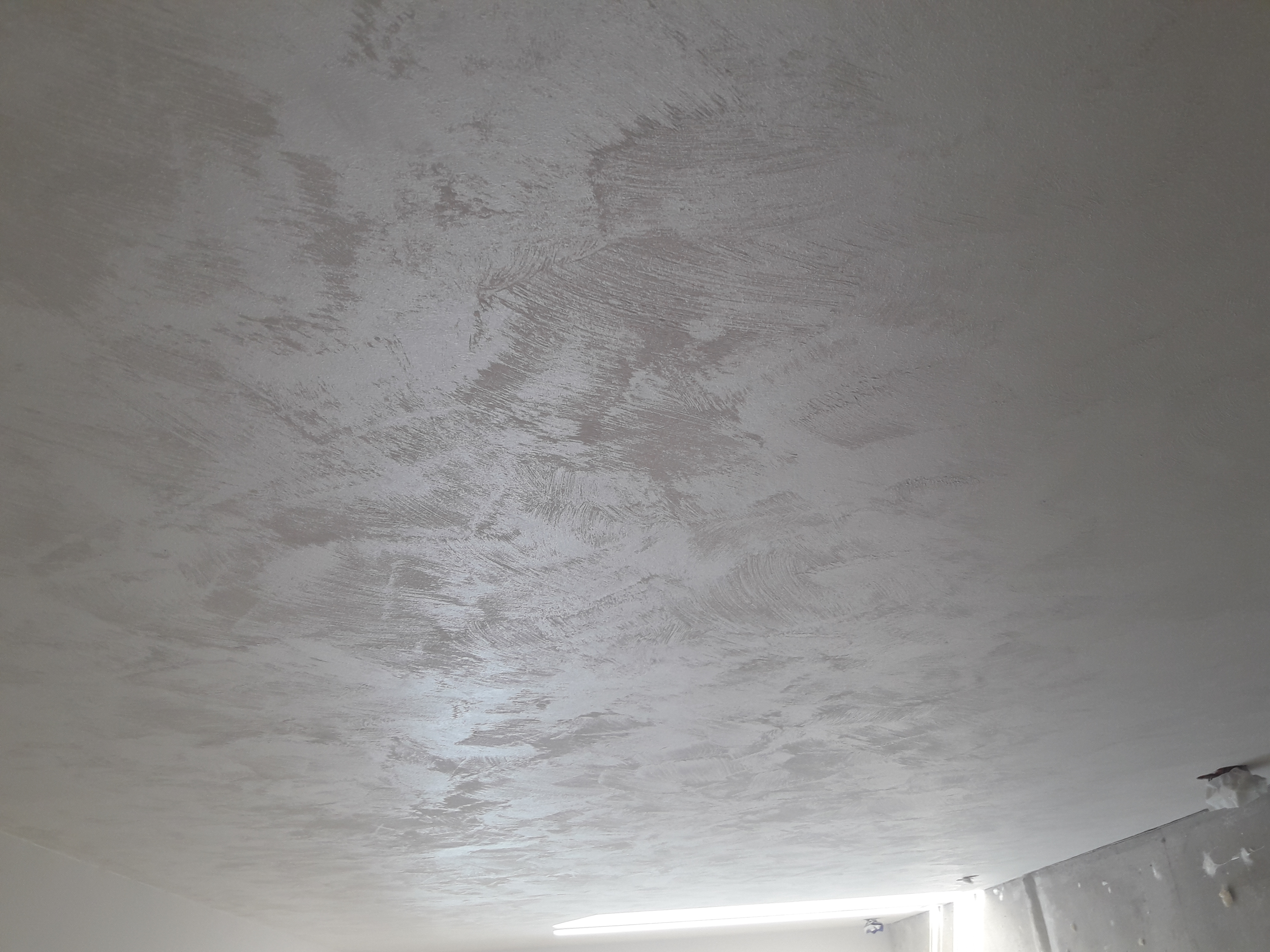 Szara, teksturowana powierzchnia sufitu po wykonaniu prac w Warszawie, widoczna faktura nakładania materiału.