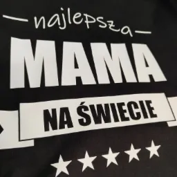 Czarna koszulka z białym nadrukiem '- najlepsza - MAMA - NA ŚWIECIE' oraz pięcioma gwiazdkami na dole, ujęcie z bliska.