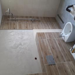 Mar-Wik - Wykończona łazienka z drewnopodobnymi płytkami, bidetem, toaletą i prysznicem; widoczny fragment drabiny malarskiej.