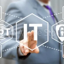 Biznesmen w szarym garniturze dotyka wirtualnego ekranu z ikonami: Big Data, IoT, IT, chmura, bezpieczeństwo i urządzenia mobilne.