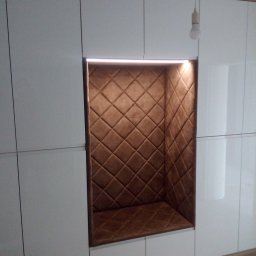 Meblomar-mikstat - Biała szafa wnękowa z podświetlaną, tapicerowaną wnęką w kolorze brązowym. Widoczna żarówka.