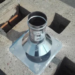 Metalowy wkład kominowy z kołnierzem uszczelniającym, zamontowany na betonowym kominie w Poznaniu, widoczne oznaczenia producenta i numery seryjne.