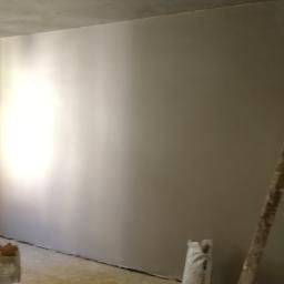 Reformas Generales - Ściana po nałożeniu gładzi, z widocznymi workami z materiałem i drewnianą drabiną, w trakcie prac wykończeniowych.