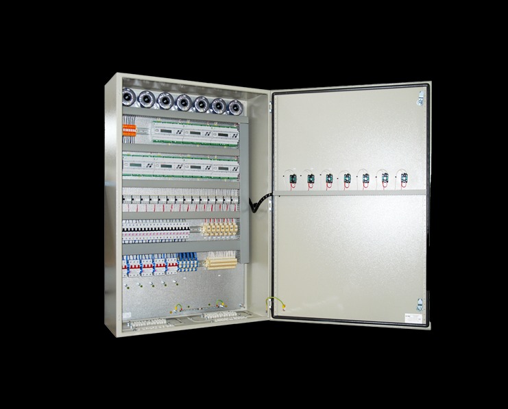 Otwarta metalowa szafa sterownicza z widocznymi elementami instalacji elektrycznej, w tym liczniki, bezpieczniki, przewody i złączki, umieszczona na czarnym tle.