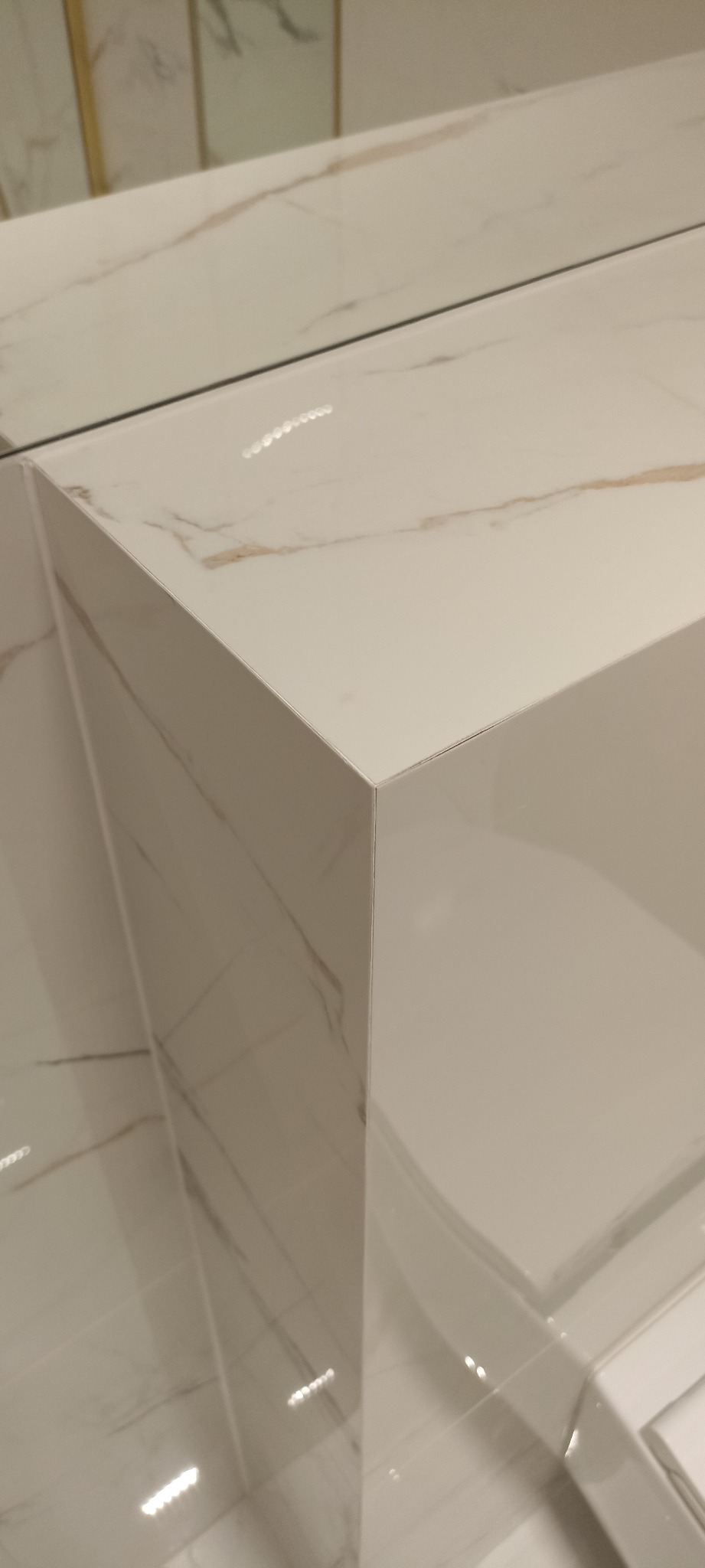 Biała umywalka nablatowa z marmurowym wzorem, ostra krawędź blatu, odbicie światła na powierzchni.