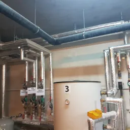 Kotłownia z widocznym zbiornikiem, rurami z izolacją, zaworami odcinającymi i rozdzielaczem C.O.