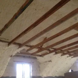 Poddasze z drewnianą konstrukcją dachu, ocieplone pianką natryskową, widok na okno dachowe.