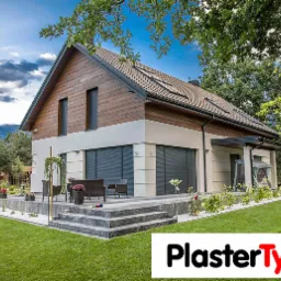 Nowoczesny dom jednorodzinny z elewacją w odcieniach bieli i drewna, z tarasem wyłożonym kamieniem i zadbanym trawnikiem, widok z ogrodu w słoneczny dzień.