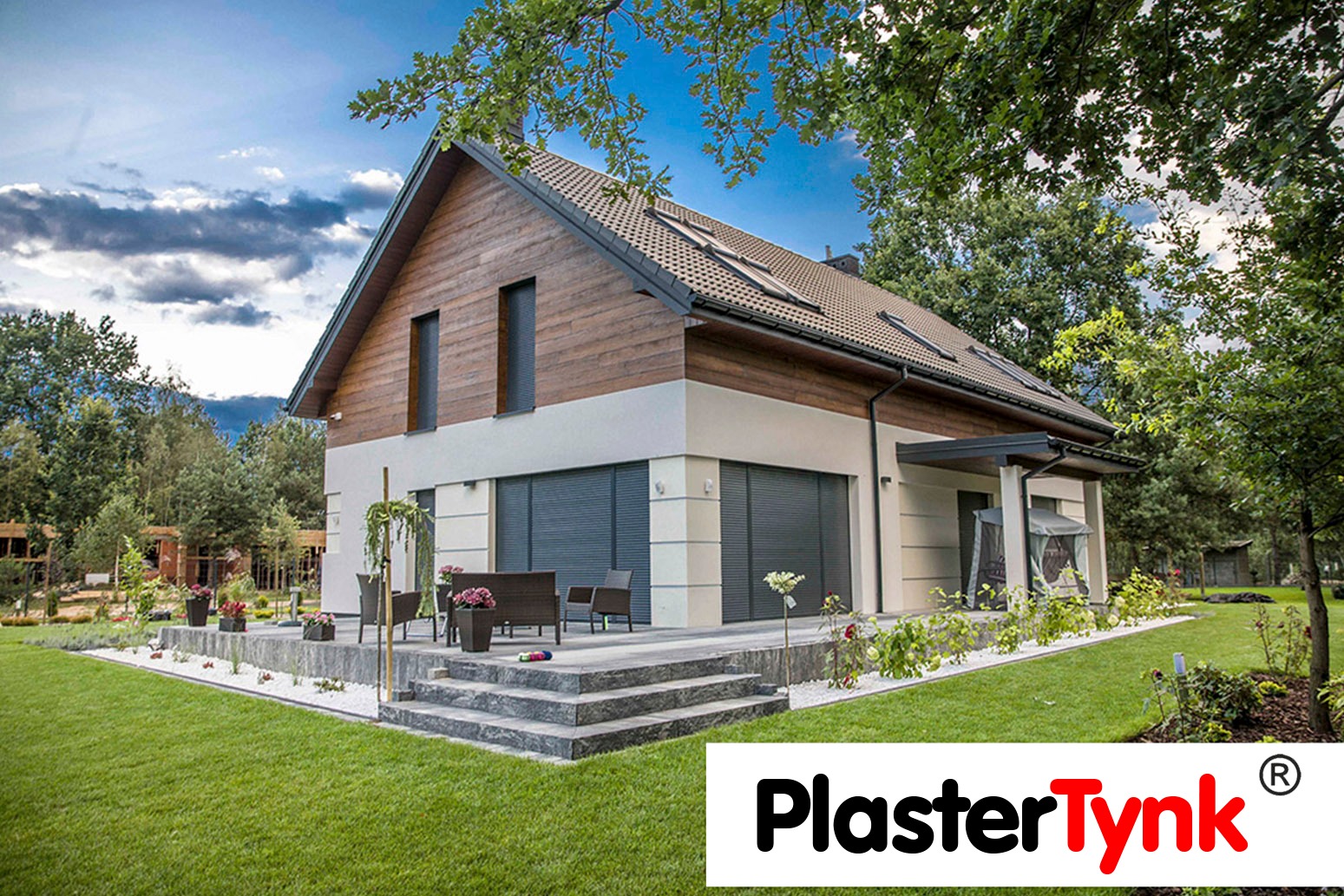 Nowoczesny dom jednorodzinny z elewacją w odcieniach bieli i drewna, z tarasem wyłożonym kamieniem i zadbanym trawnikiem, widok z ogrodu w słoneczny dzień.