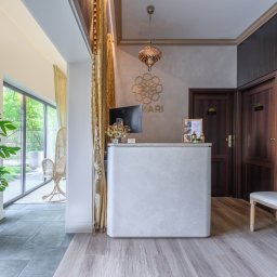 Dron4Pic - Jasne, eleganckie wnętrze z recepcją, dekoracyjną lampą i roślinami, widok na ogród przez przeszklone drzwi