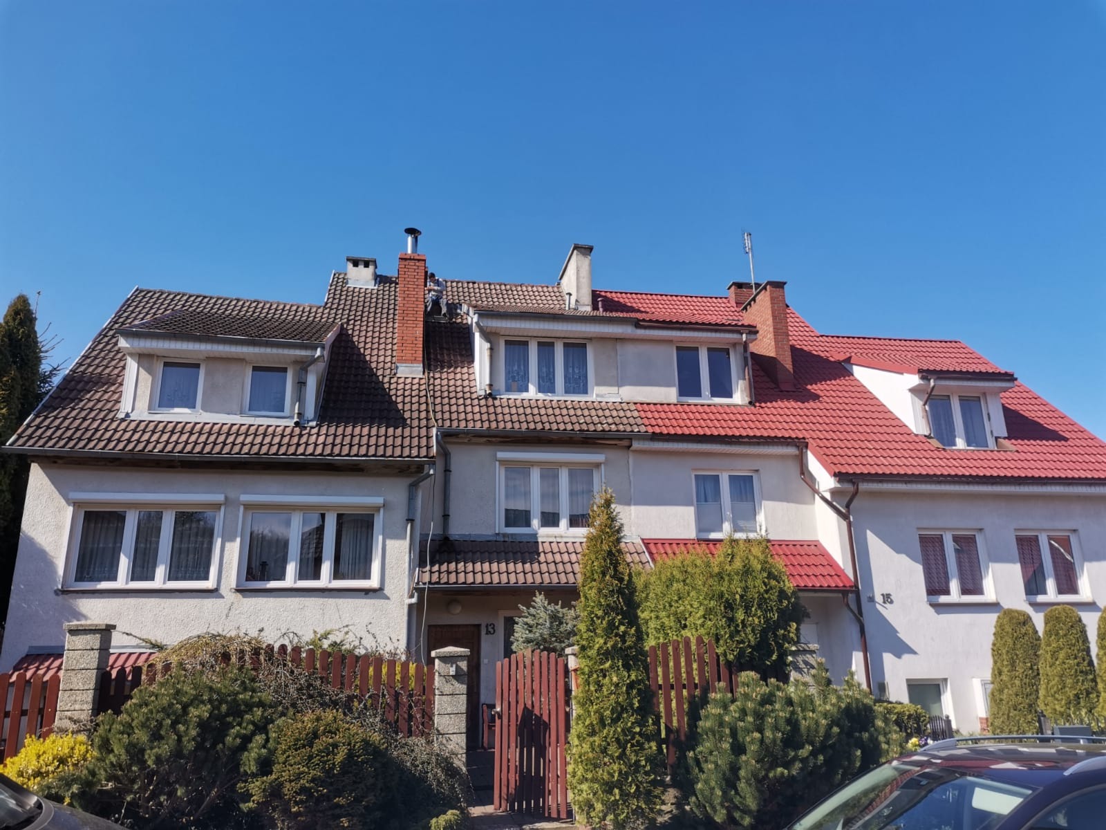 Szeregówka domów: pierwszy z elewacją i dachem przed renowacją, środkowy częściowo odnowiony, a ostatni z nową czerwoną dachówką i jasną elewacją.