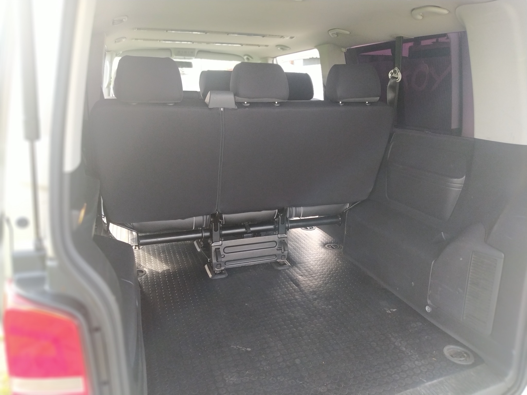 Wnętrze busa z trzema rzędami siedzeń i gumową podłogą w kształcie okręgów, widok od tyłu.