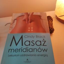 Masaż relaksacyjny - Książka o masażu meridianów Cindy Black, obok szyszka i lampka solna