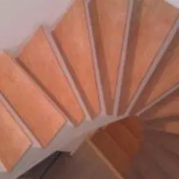 Spiralne schody drewniane, widok z g&oacute;ry. Naturalny odcień drewna, jasne tło ścian. Ujęcie podkreśla zakrzywiony kształt i precyzję wykonania.