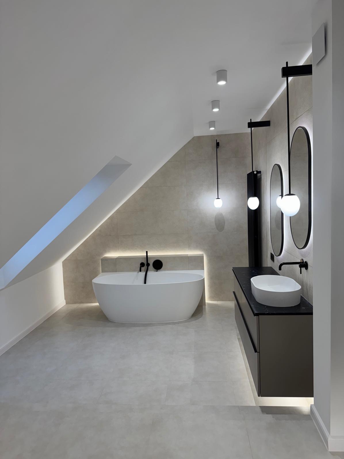 Nowoczesna łazienka na poddaszu z wolnostojącą wanną, umywalką nablatową i podświetlanymi lustrami. Minimalistyczny design z elementami czerni i bieli.