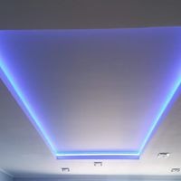 Podwieszany sufit z oświetleniem LED w kolorze niebieskim, tworzący trapezoidalny kształt. Widoczne cztery punkty oświetleniowe w suficie.
