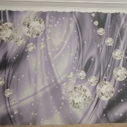 Ściana z tapetą w odcieniach fioletu i szarości, zdobiona motywem diamentów i gwiazd, otoczona białymi listwami przypodłogowymi i sufitowymi.