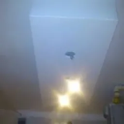 Biały, prostokątny sufit podwieszany z trzema punktami świetlnymi, widoczne niedoskonałości w wykończeniu, słaba jakość zdjęcia.