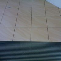 Ułożone płytki podłogowe w odcieniach beżu z widocznymi fugami, przykryte folią ochronną w dolnej części kadru.