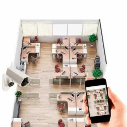 Kamera monitoringu zamontowana w biurze, widok z góry na stanowiska pracy, osoba trzyma telefon z podglądem z kamery.