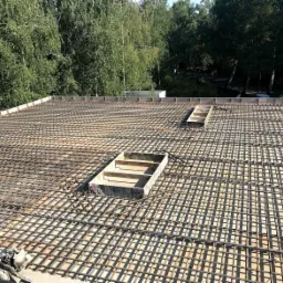 Siatka zbrojeniowa na stropie budynku w Sosnowcu, przygotowana do zalania betonem, z widocznymi otworami na przyszłe instalacje.