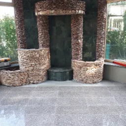 Wykończona wnęka z zielonego marmuru i obłożona kamieniem, z nową podłogą z płytek, widok na okno i skrzynkę narzędziową.