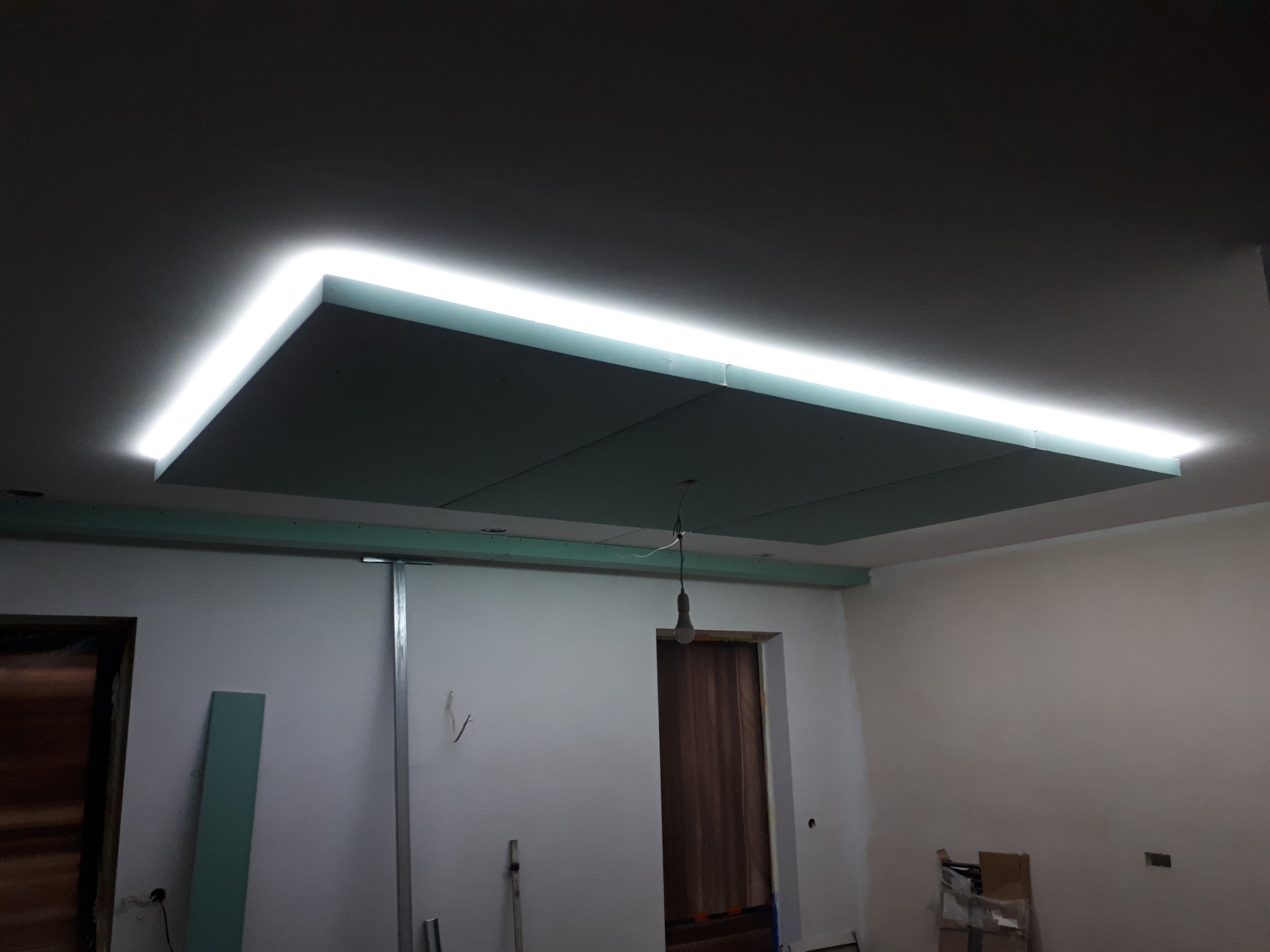 Podwieszany sufit z płyt gipsowo-kartonowych z oświetleniem LED w trakcie montażu, widoczne profile i niedokończone ściany.