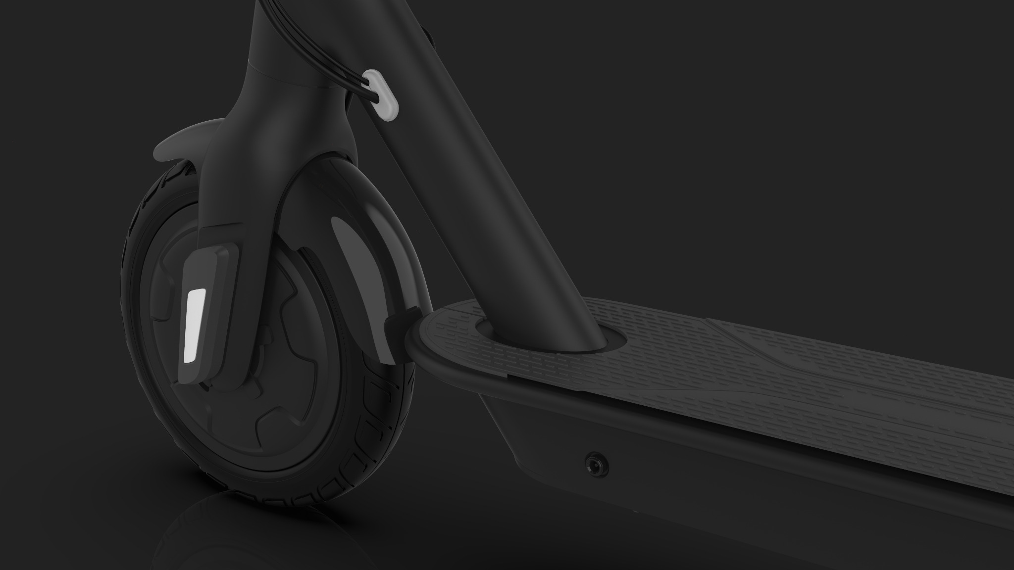 Szczegółowe ujęcie przedniego koła i podestu czarnej hulajnogi elektrycznej na ciemnym tle, ukazujące detale bieżnika opony i antypoślizgowej powierzchni podestu.