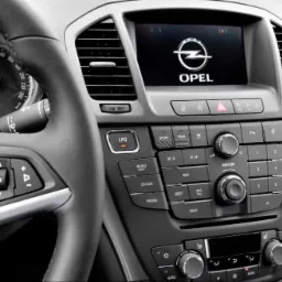 Wnętrze samochodu Opel z widocznym panelem centralnym, kierownicą i włączonym wyświetlaczem z logo marki, przycisk LPG podświetlony.