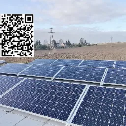 Instalacja paneli słonecznych na dachu budynku, widok z góry, w tle pole uprawne i słupy energetyczne, w lewym górnym rogu logo firmy z kodem QR.
