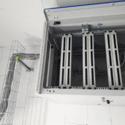 Szafa serwerowa z panelami krosowniczymi i okablowaniem w korytku, zamontowana w pomieszczeniu w Pruszkowie. Widoczny klucz w zamku szafy.