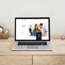 Laptop na drewnianym biurku prezentuje stronę internetową kancelarii adwokackiej z informacjami o skuteczności i zadowoleniu klientów, obok złota dekoracja i roślina w białej doniczce.