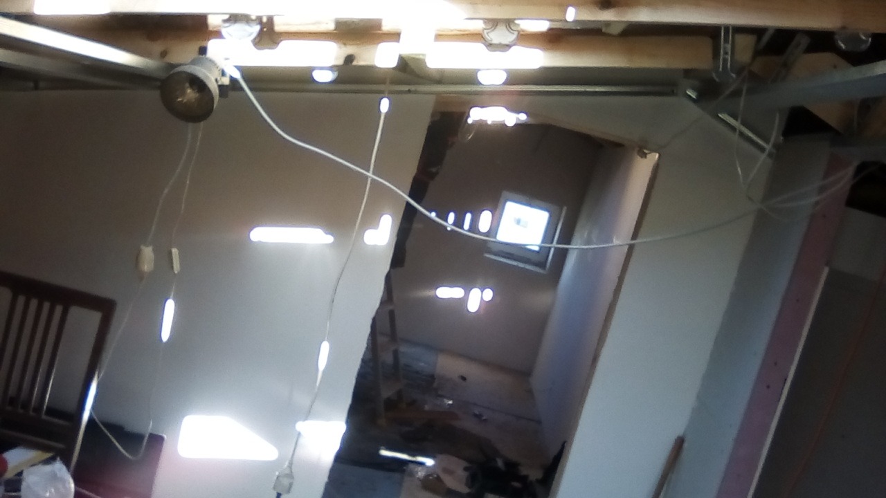 Poddasze w trakcie prac remontowych, widoczne oświetlenie robocze, niedokończone ściany i elementy konstrukcyjne dachu.