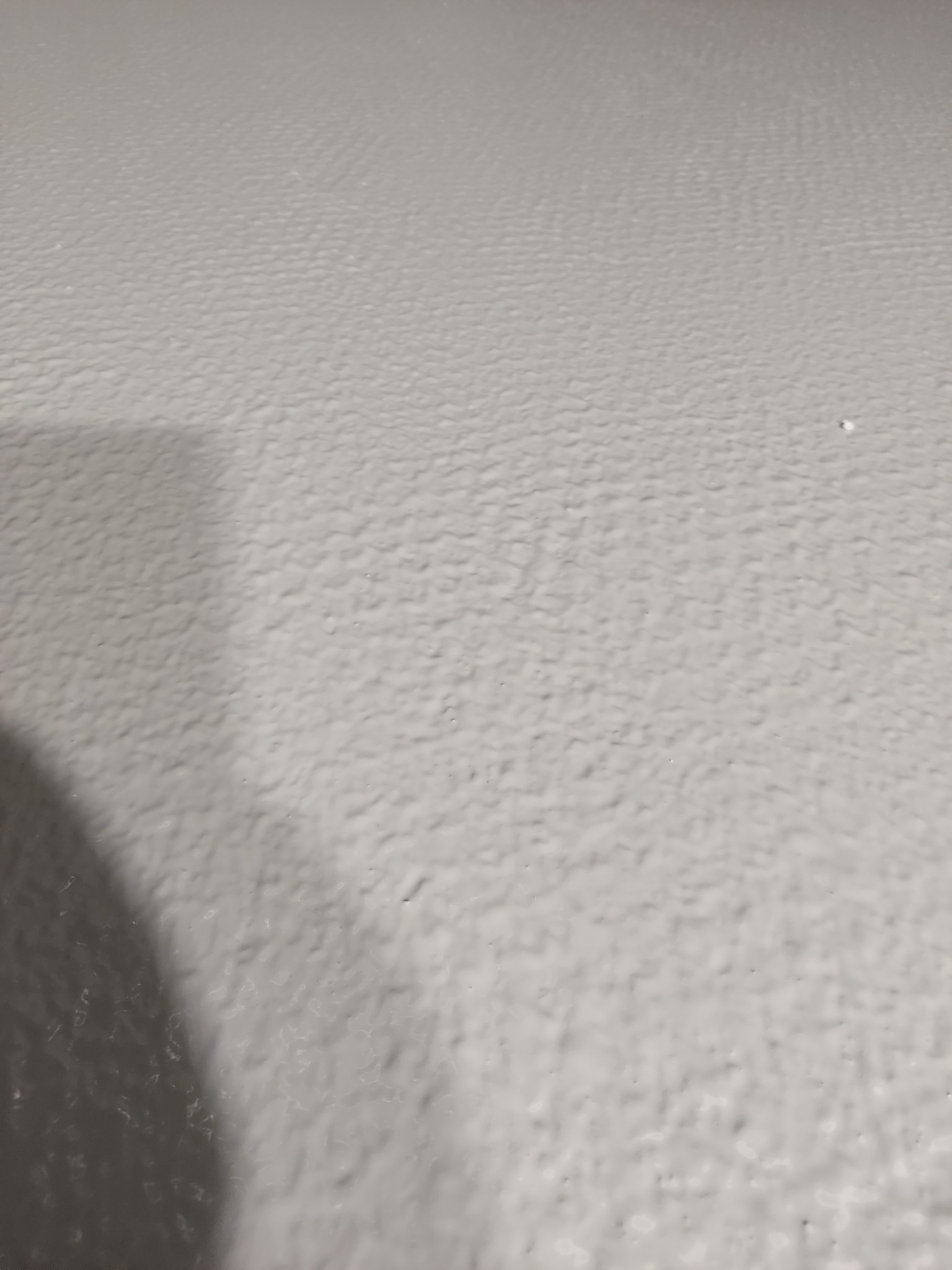 Szara, jednolita powierzchnia z delikatną fakturą, prawdopodobnie podłoga, wykonana w Sochaczewie. Widoczny cień w lewym dolnym rogu.