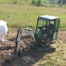 KANMAKS - Mini koparka Bobcat E19 w trakcie prac ziemnych przy zbiorniku, prawdopodobnie podczas instalacji w gruncie.