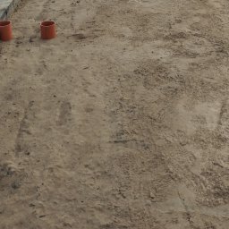 KANMAKS - Dwa pomarańczowe rury kanalizacyjne leżące na piasku z widocznymi śladami stóp.