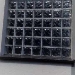 Ściana z wbudowanym oknem z luksferów, widoczne z bliska, z delikatnym oświetleniem.