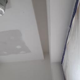 P.P.U.H Wojkoz - Fragment sufitu po szpachlowaniu, z widocznymi łatami i przygotowaniem do malowania, zabezpieczone folią okno w rogu.