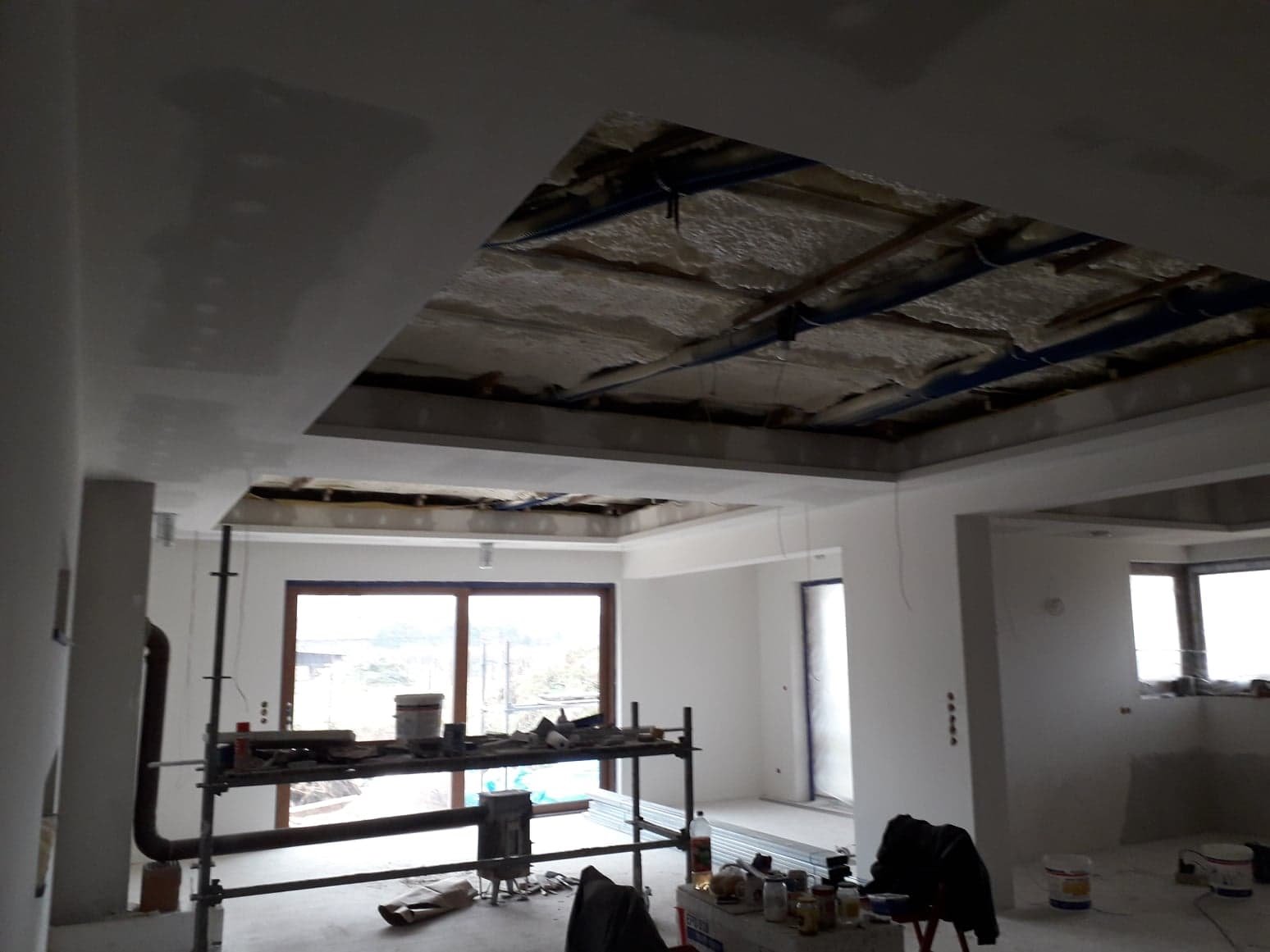 Montaż sufitu podwieszanego z widoczną instalacją w Częstochowie, widok na częściowo zakryty strop i rusztowanie.