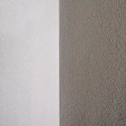 Fragment ściany z nałożonym tynkiem: po lewej stronie biały, po prawej szary o wyraźnej fakturze.