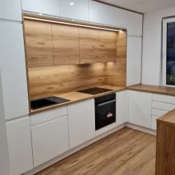 Nowoczesna, jasna kuchnia z białymi szafkami i drewnianymi blatami, oświetleniem LED podszafkowym i parkietem w odcieniach brązu.