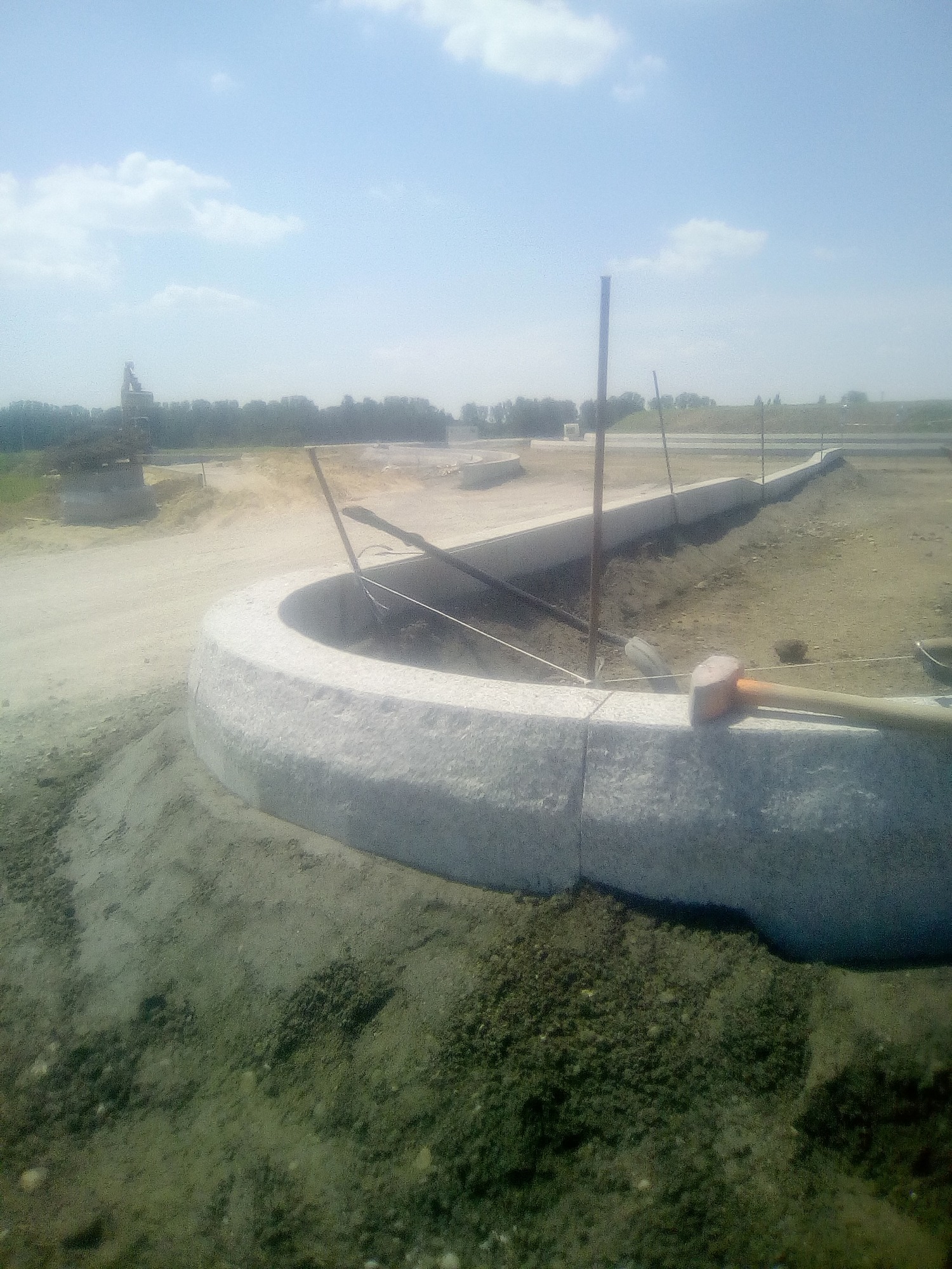 Montaż obrzeża z kamienia naturalnego na placu budowy, widoczny gumowy młotek i szpilki stabilizujące.