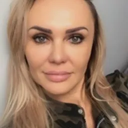 Portret kobiety z blond włosami, ubrana w kurtkę moro, z delikatnym makijażem i jasnymi oczami, skierowana w stronę obiektywu.