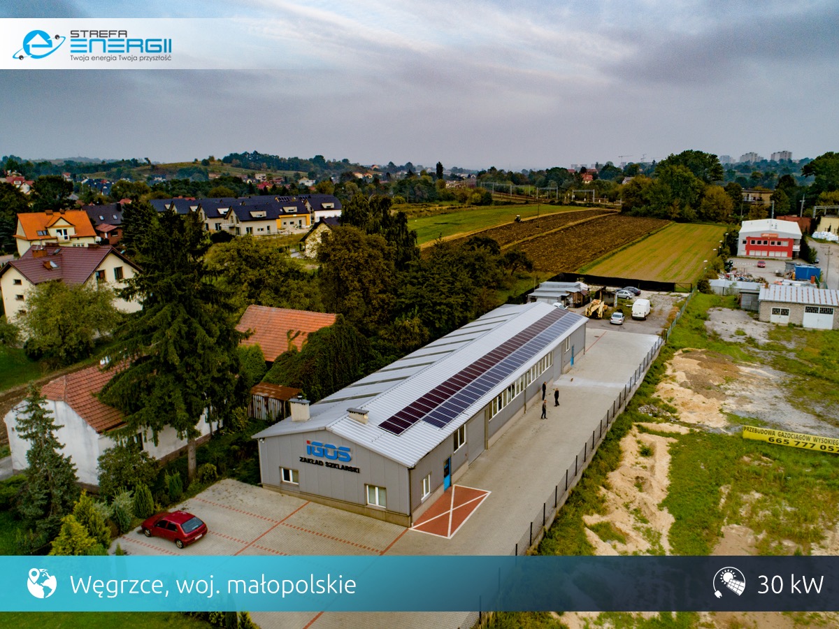 Widok z drona na budynek zakładu szklarskiego z panelami słonecznymi na dachu, Węgrzce, województwo małopolskie, moc instalacji 30 kW.