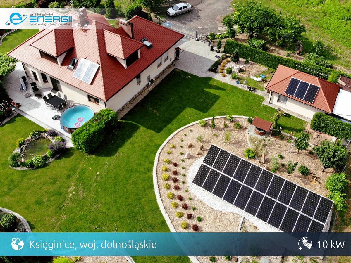 Widok z lotu ptaka na dom z panelami słonecznymi na dachu i naziemną instalacją, basen ogrodowy z dmuchanym kołem, staw, studnia i zadbany trawnik w Księginicach, woj. dolnośląskie. Moc instalacji...