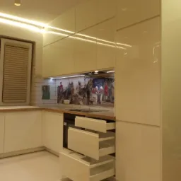 Nowoczesna kuchnia na wymiar z białymi, lakierowanymi frontami, otwartymi szufladami cargo i dekoracyjnym panelem ściennym z motywem historycznym.